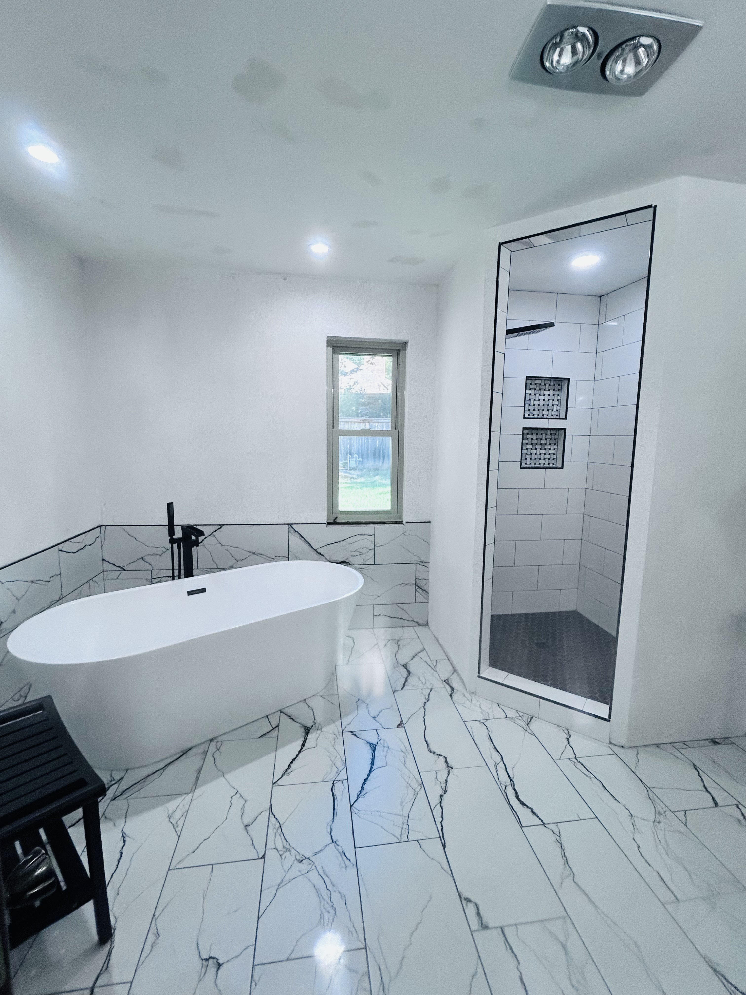 Remodeled bathroom with marble tile, freestanding tub, and walk-in shower in a Tulsa home