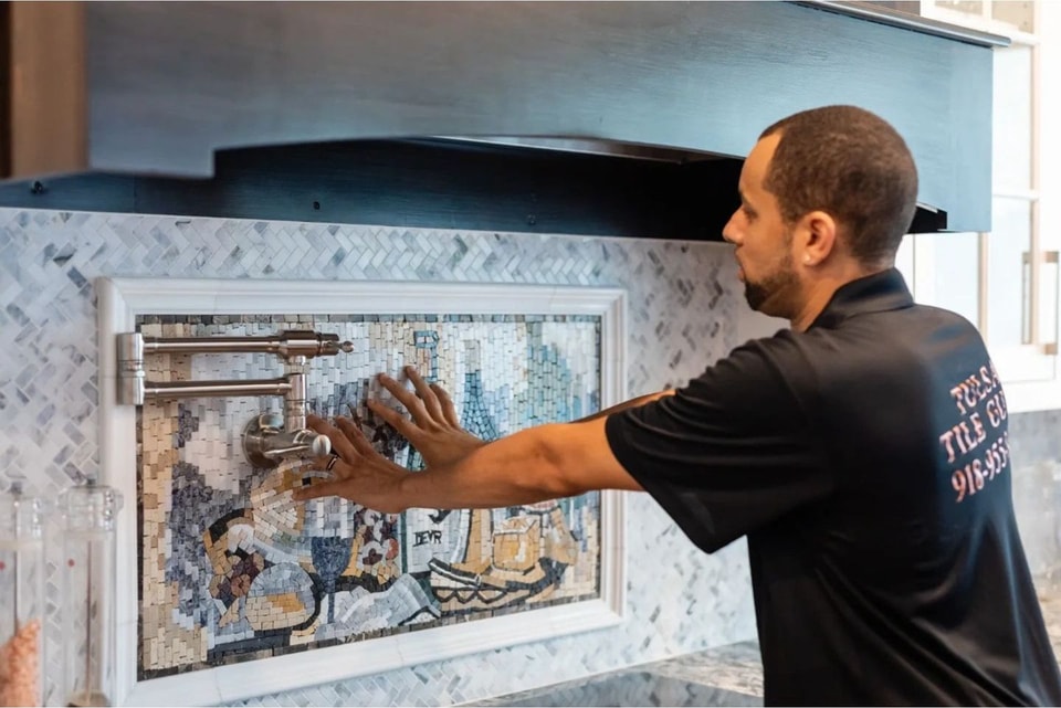 Craftsman setting a decorative mosaic tile mural behind a kitchen range