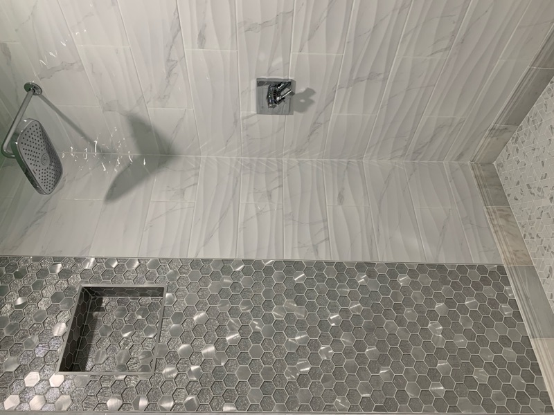 Shower interior with hexagon accent tile wall, built-in niche, and rain showerhead